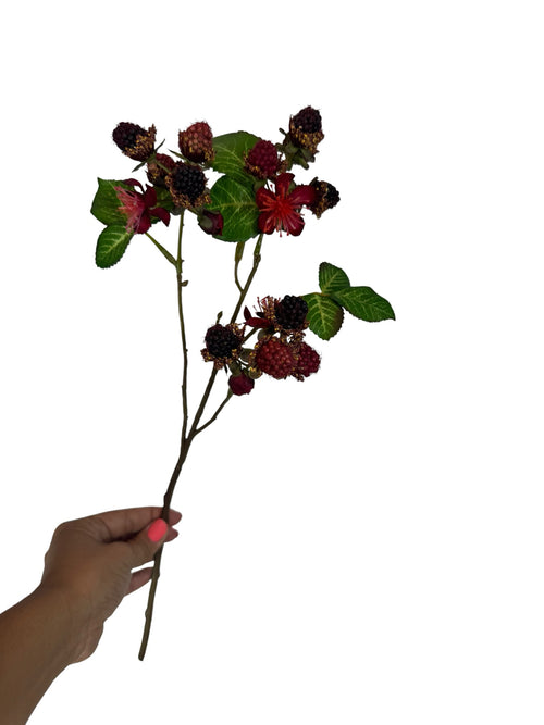 Artificial Bloom decorative blackberry stem with dark berries, red blossoms, and green leaves held by a hand.