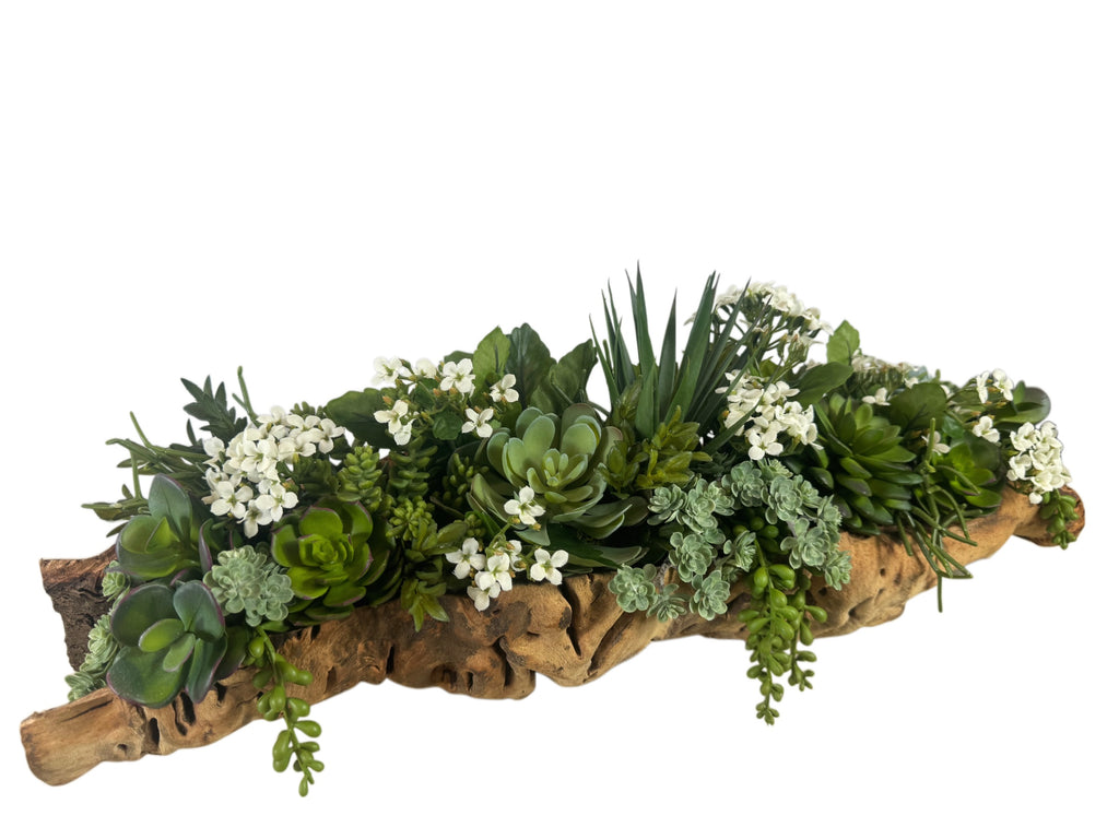 Artificial Bloom succulent arrangement featuring vibrant green faux plants and white flowers in a rustic driftwood base.