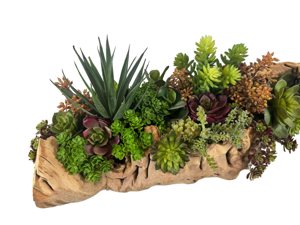 Artificial Bloom succulent arrangement featuring green and purple faux plants in a rustic natural driftwood base.