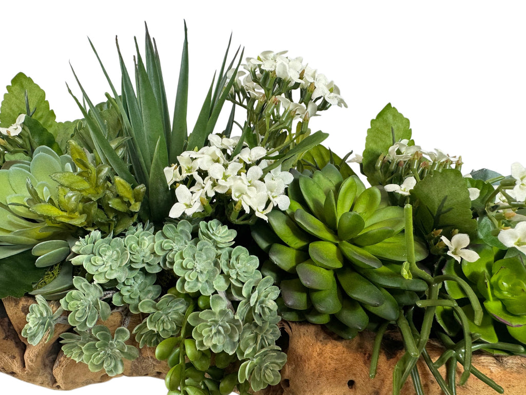 Artificial Bloom succulent arrangement featuring vibrant green faux plants and white flowers in a rustic driftwood base.