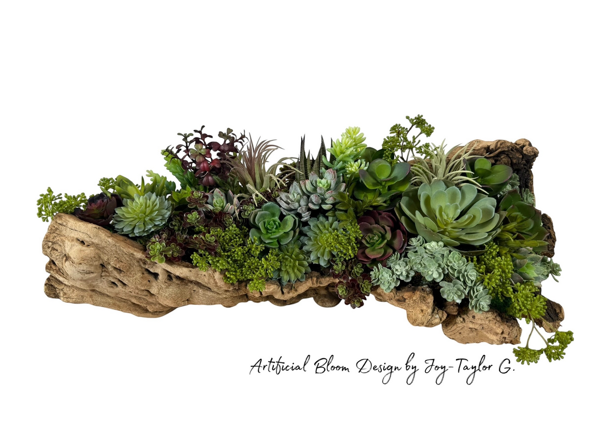 Artificial Bloom succulent arrangement featuring diverse green and burgundy faux plants in a rustic driftwood planter.