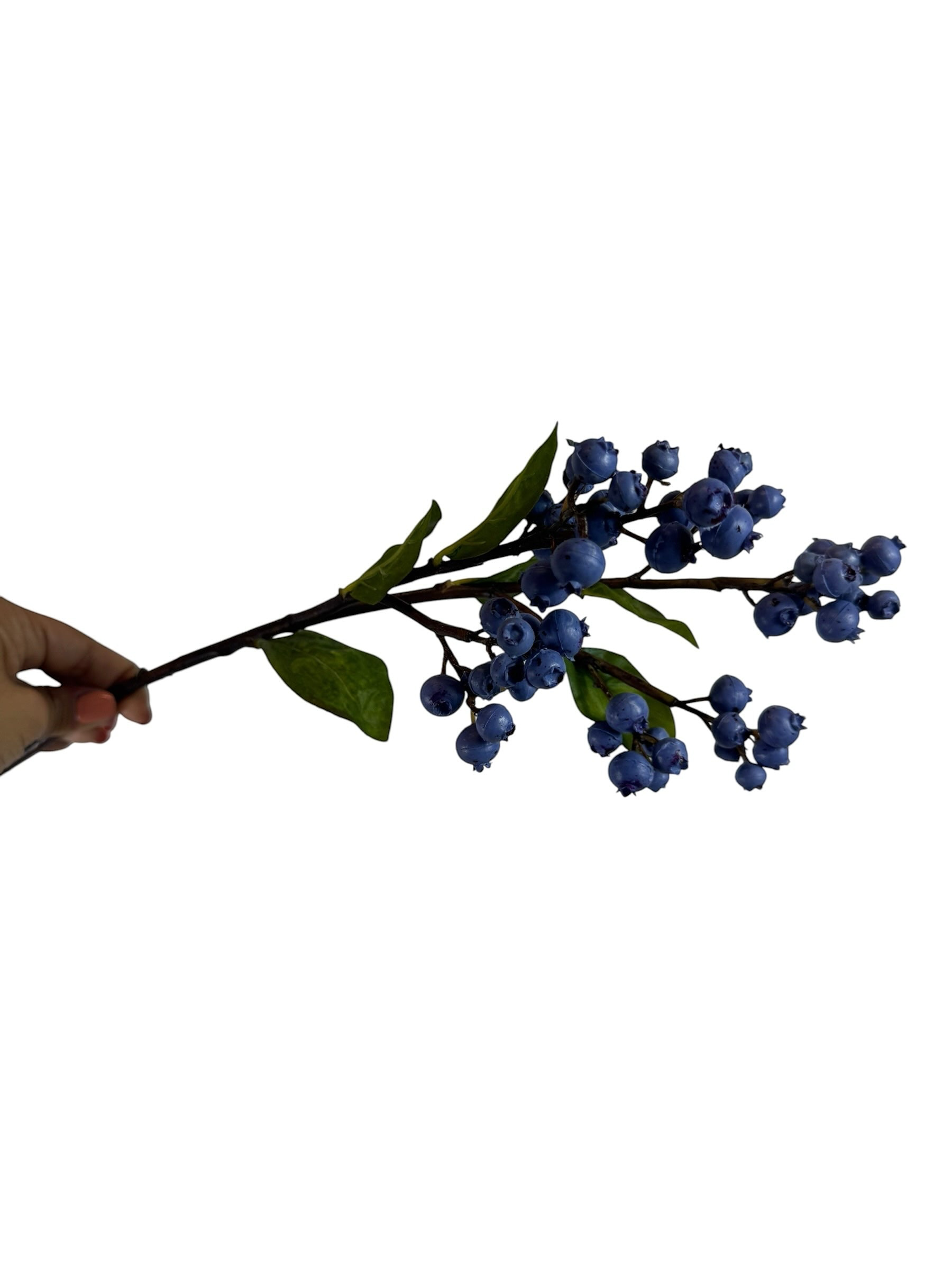 Artificial Bloom faux blueberry branch with realistic deep blue berries and green leaves held by a hand