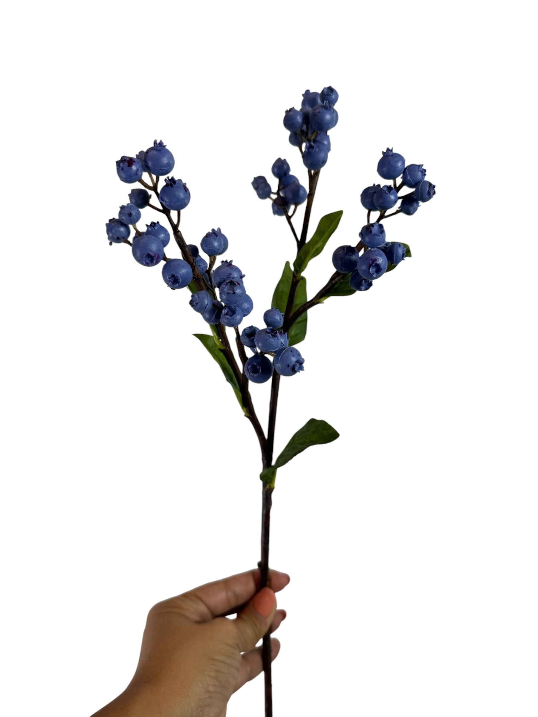 Artificial Bloom faux blueberry stem with realistic deep blue berries and green leaves held by a hand