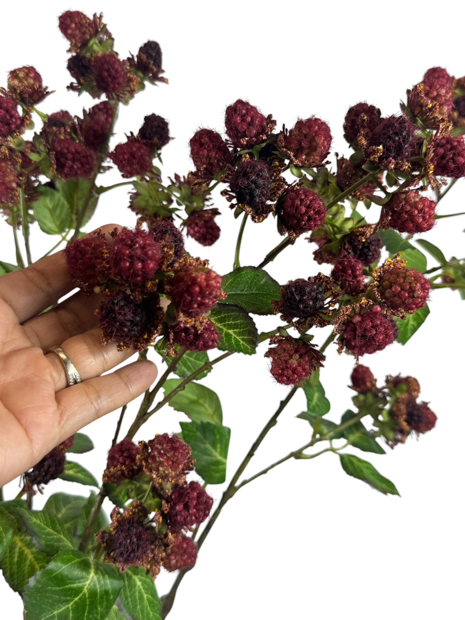 Artificial Bloom 30.5-inch tall faux raspberry spray with deep red textured berries and green leaves held by a hand