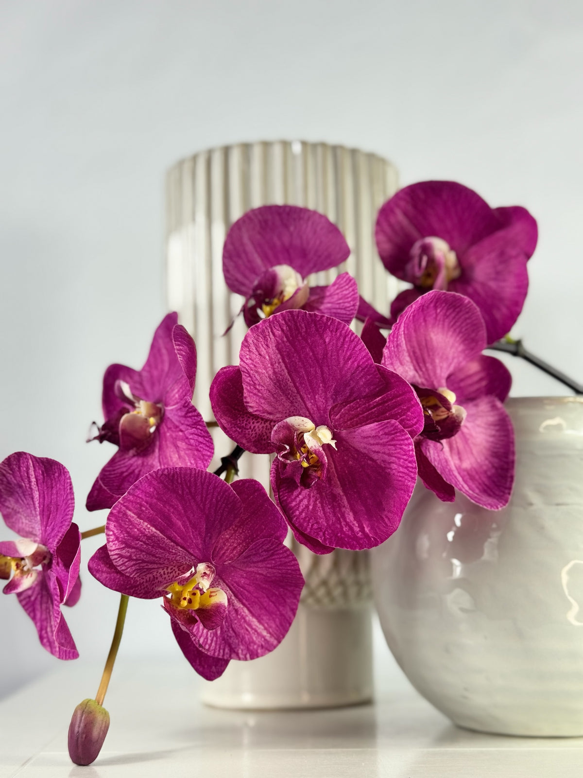 Artificial Bloom magenta Phalaenopsis orchid arrangement with silk-feel petals in a white textured ceramic vase