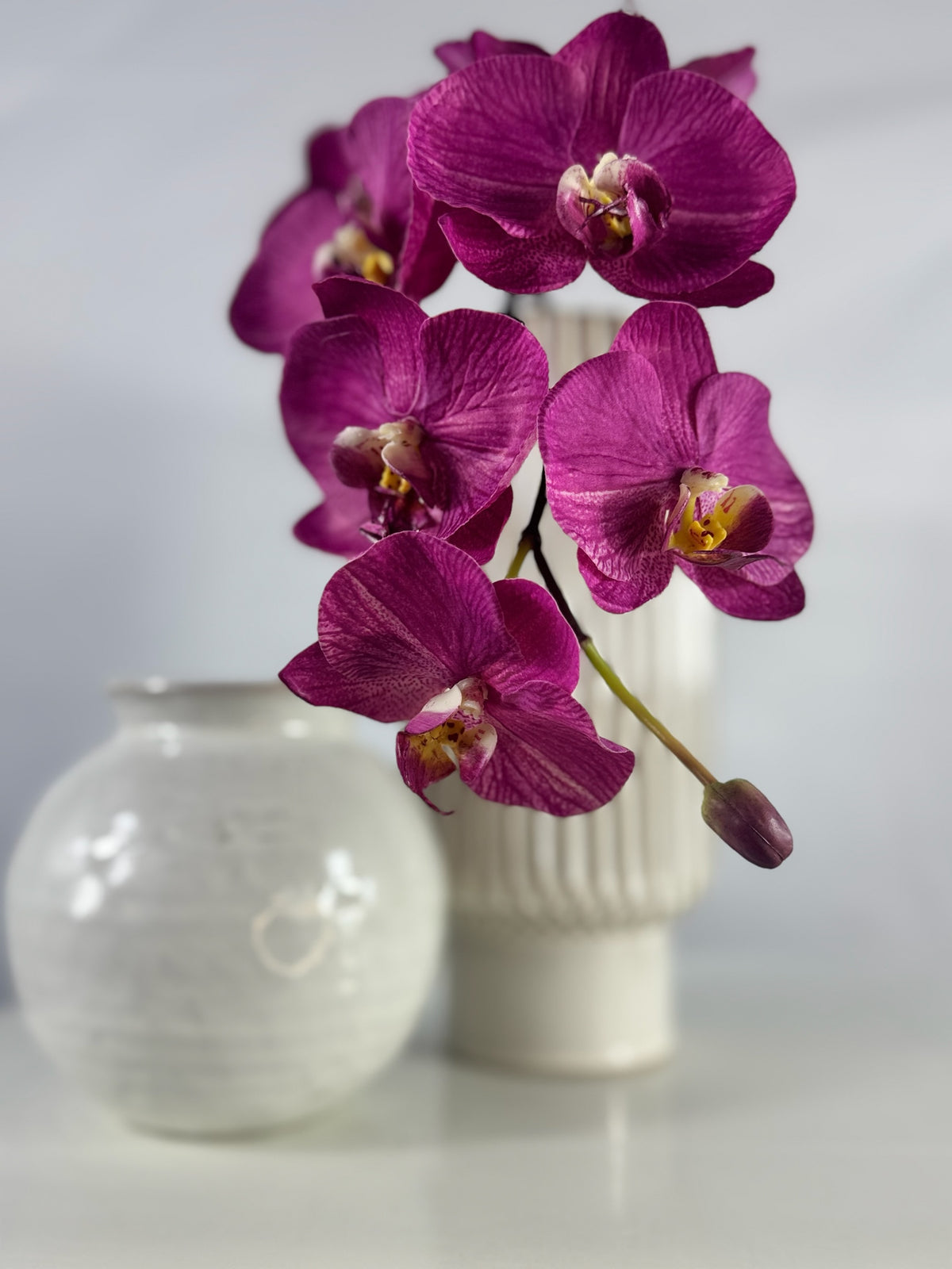 Artificial Bloom magenta Phalaenopsis orchid in a white ribbed vase, featuring realistic silk-feel petals.