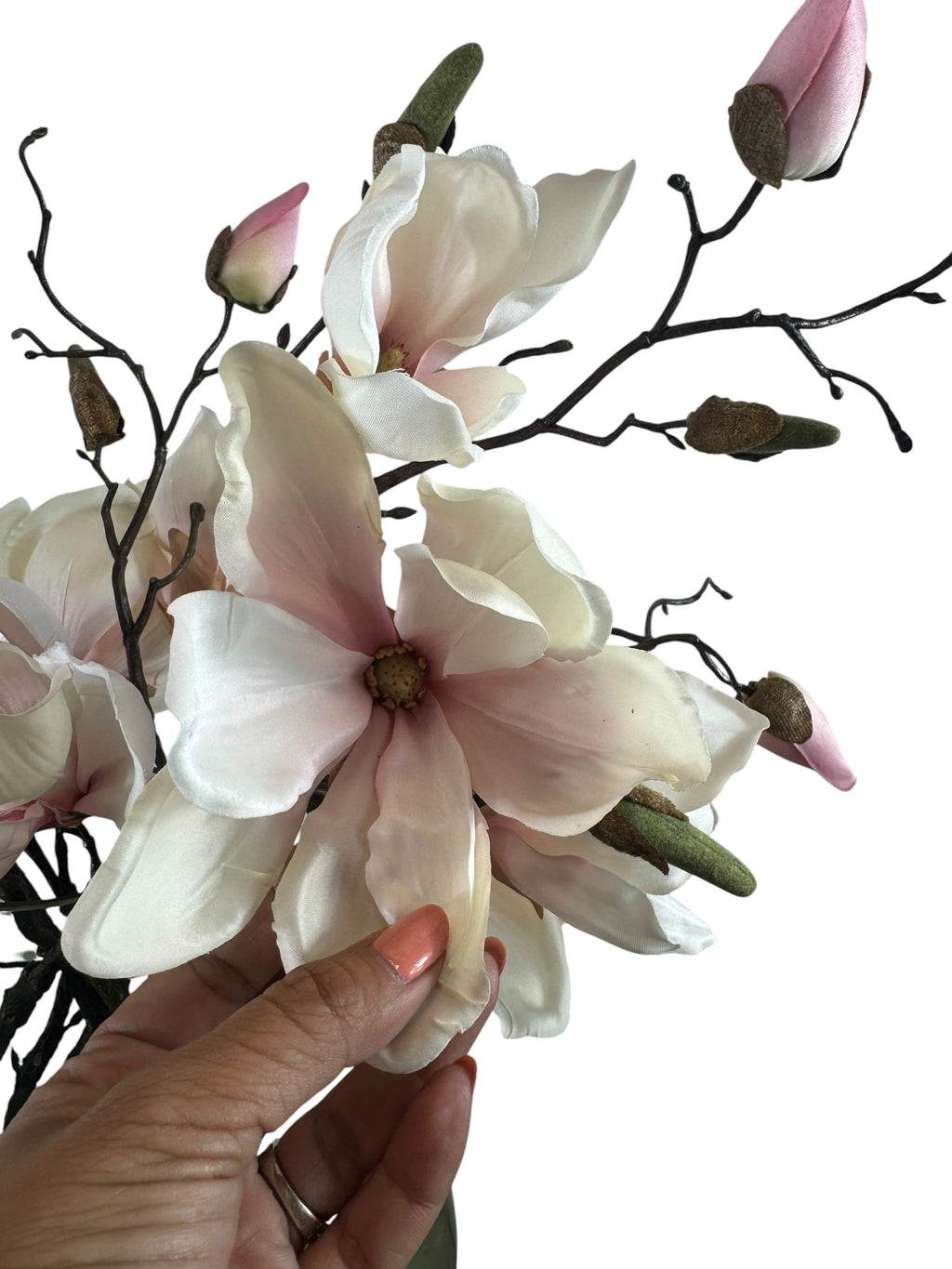 Artificial Bloom magnolia stem with creamy white and pink petals, textured buds, and a dark branch held by a hand.