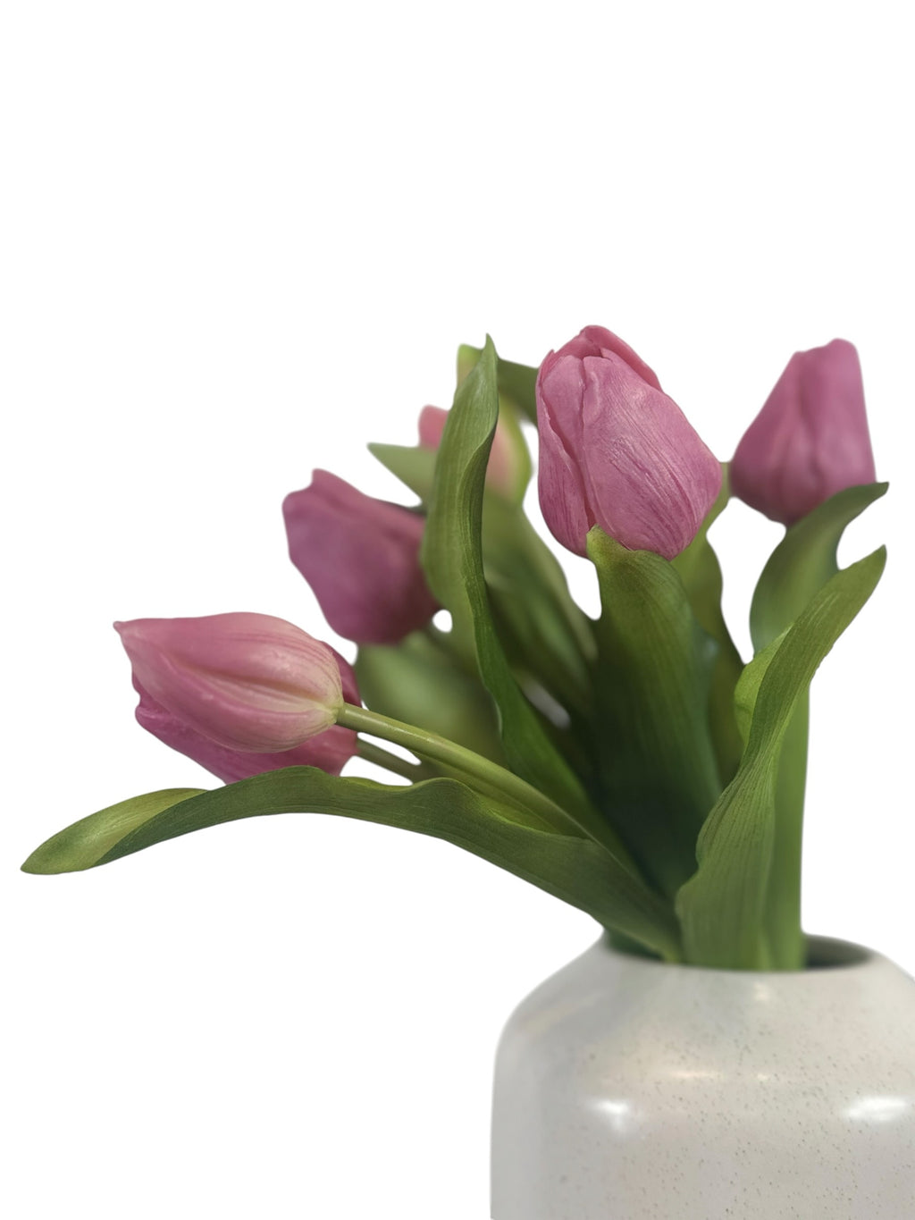 Artificial Bloom bouquet of realistic pink tulips with green foliage in a white ceramic vase against a white background