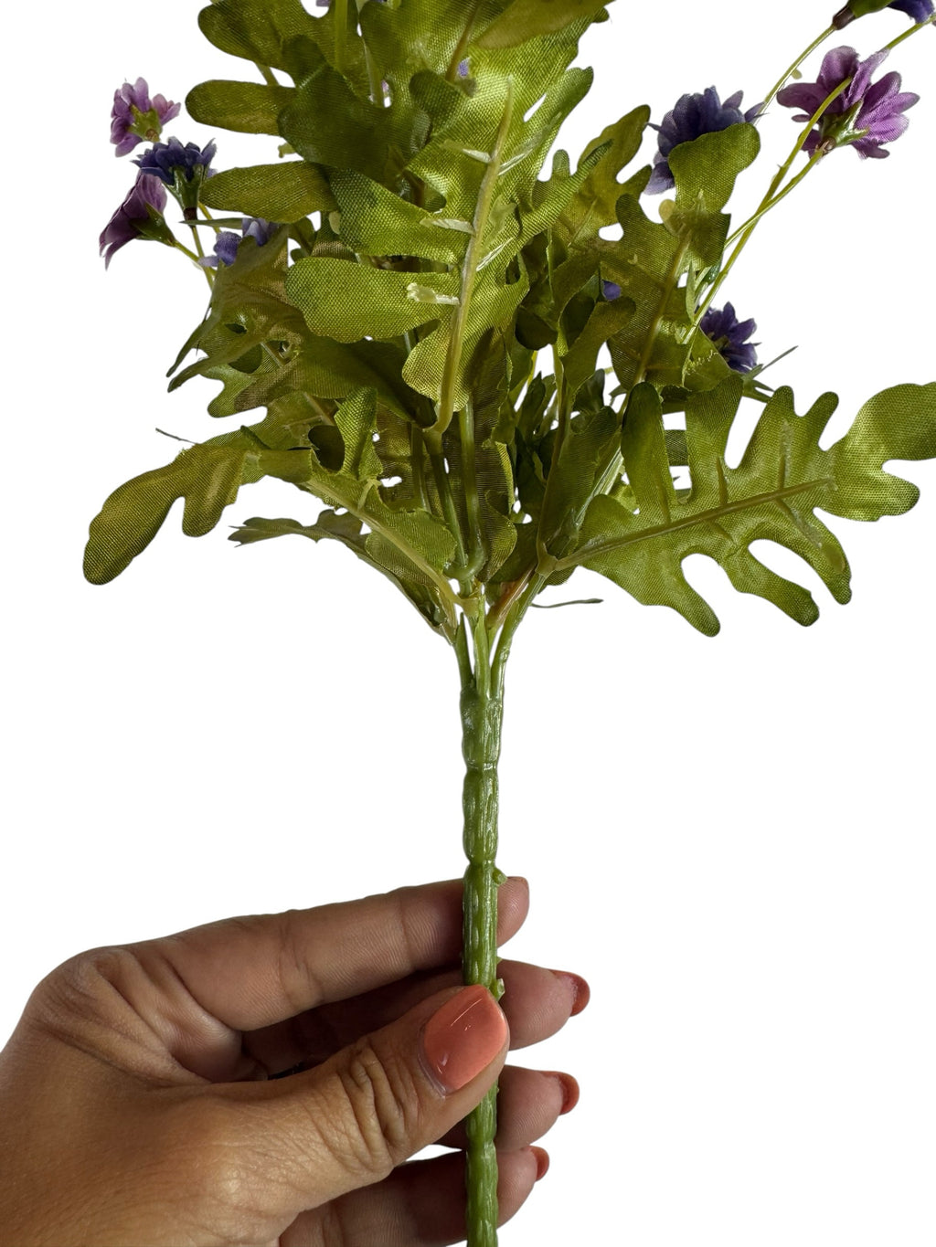 Artificial Bloom artificial daisy bouquet with purple flowers and green fabric foliage held by a hand