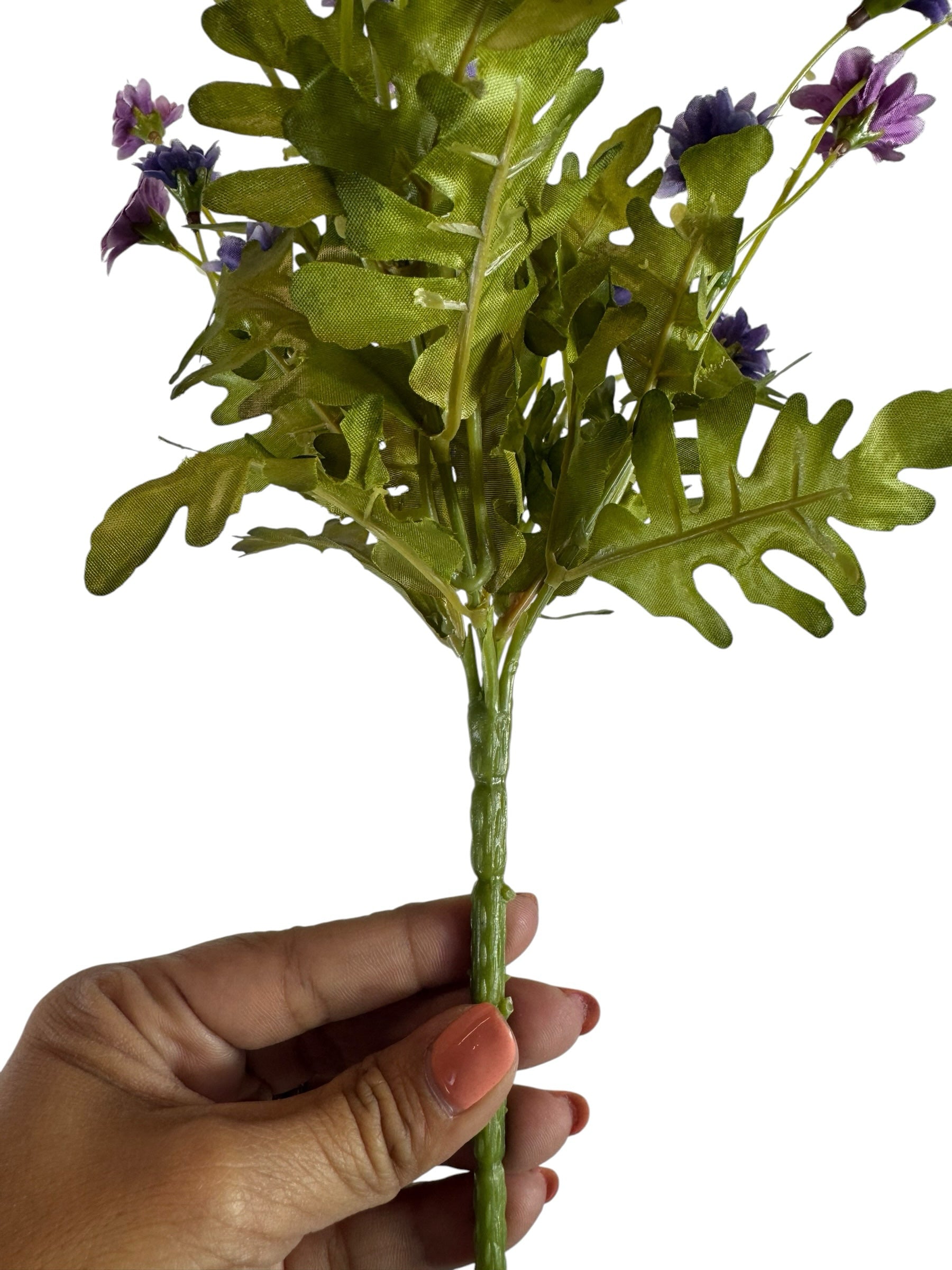 Artificial Bloom artificial daisy bouquet with purple flowers and green fabric foliage held by a hand