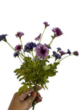 Artificial Bloom purple and lavender fabric daisy bouquet held in hand against a white background