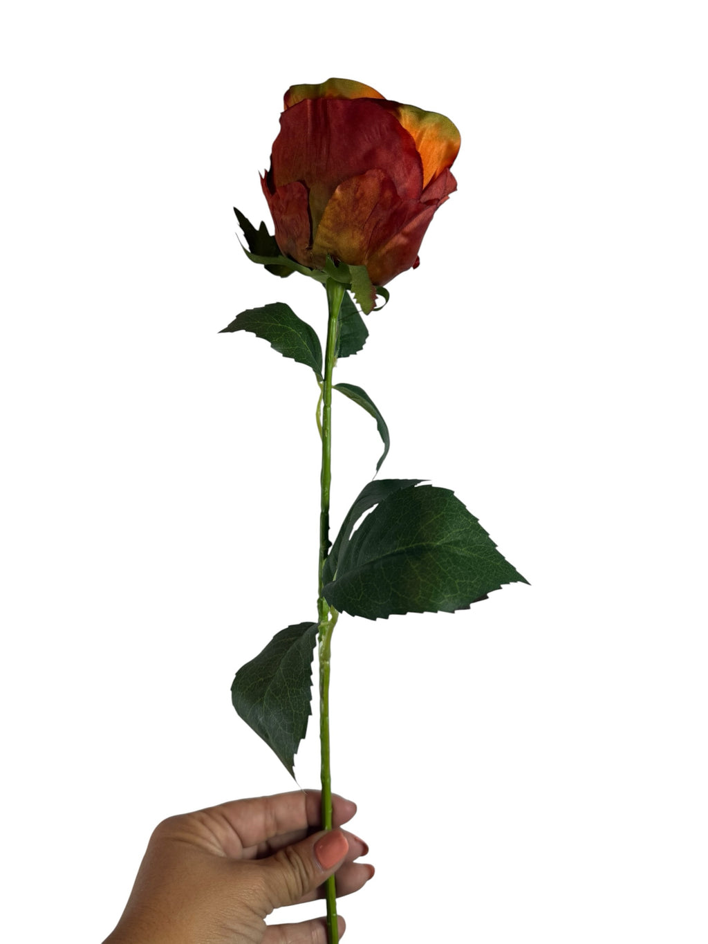 Artificial Bloom rust-orange silk rose stem with realistic green leaves held by a hand against a white background