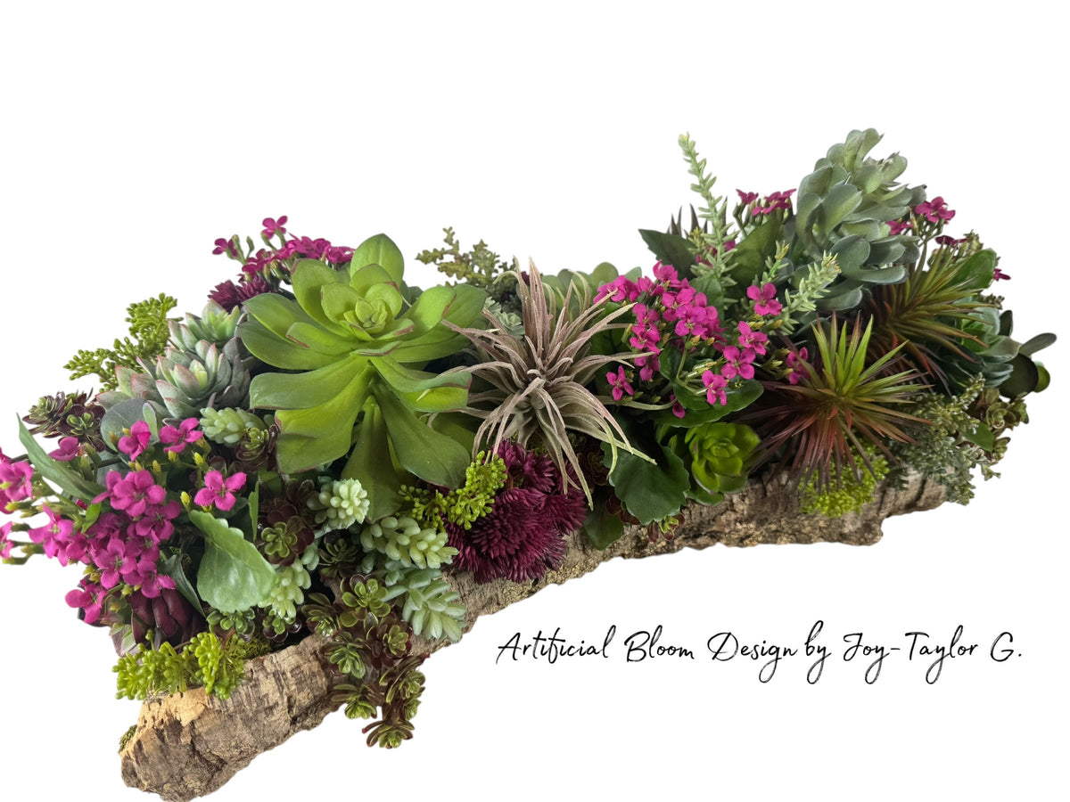 Artificial Bloom succulent centerpiece with magenta flowers and green foliage in a rustic natural cork bark base.
