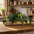 Artificial Bloom succulent arrangement featuring echeveria and agave in a rustic driftwood base on a wooden table.