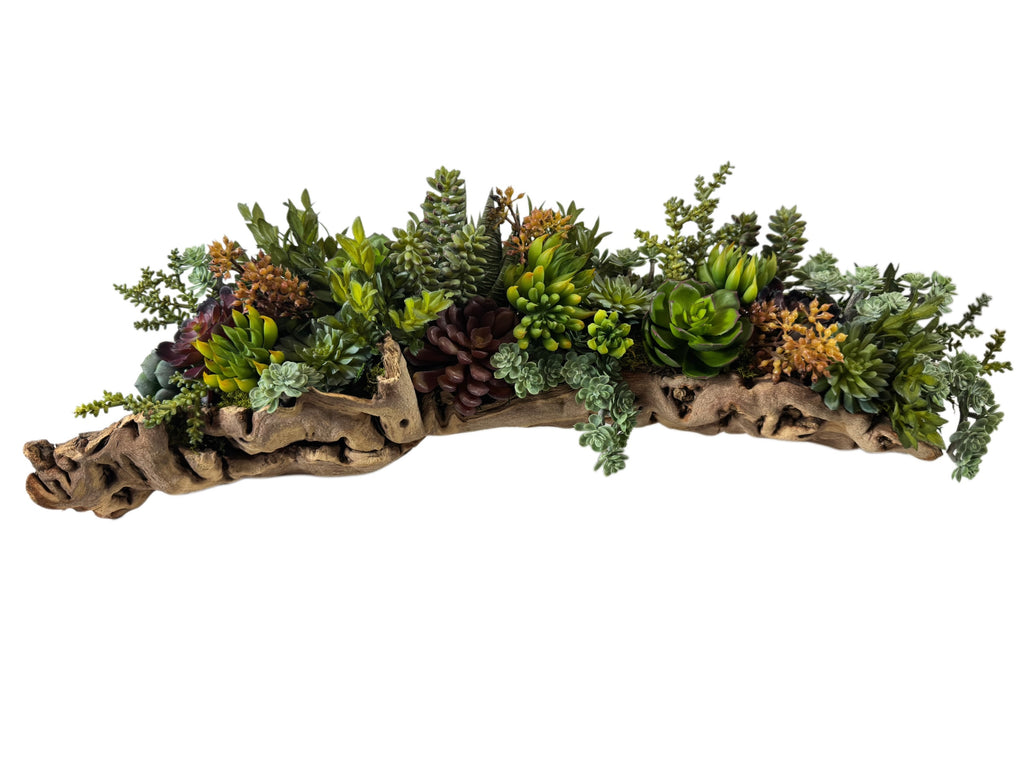 Artificial Bloom succulent arrangement featuring green, burgundy, and gold plants in a rustic natural driftwood planter.