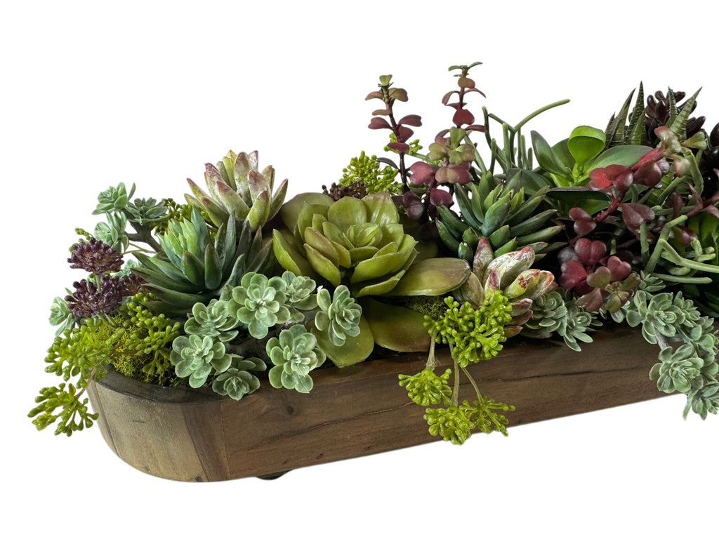 Artificial Bloom succulent garden featuring green and burgundy faux plants in a rustic wooden trough centerpiece.