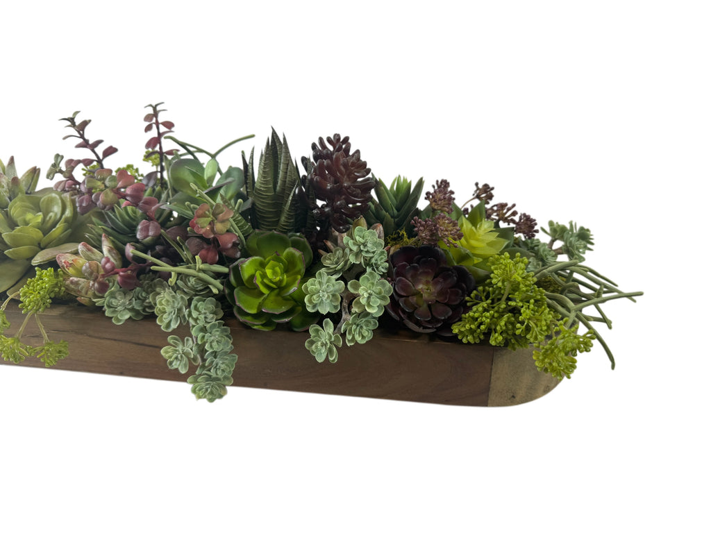 Artificial Bloom succulent arrangement featuring green and burgundy faux plants in a rustic wooden trough planter.